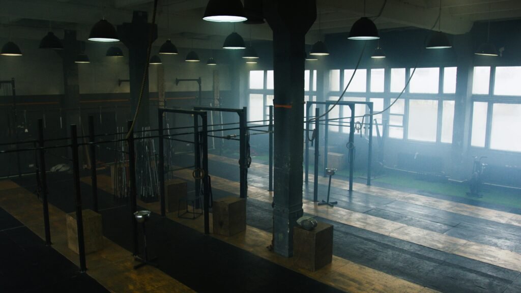 Spacious industrial-style gym interior with no people, showcasing equipment and natural light.